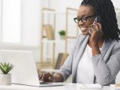 Businesswoman Talking On Phone Working On Laptop In Office