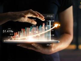 Businessman holding tablet and showing a growing virtual hologram of statistics, graph and chart with arrow up on dark background. Stock market. Business growth, planing and strategy concept.