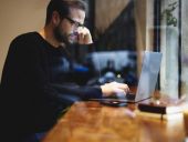 Intelligent copywriter thinking about writing new ideas for business project using modern laptop while searching information on website sources. Freelancer using high speed internet connection