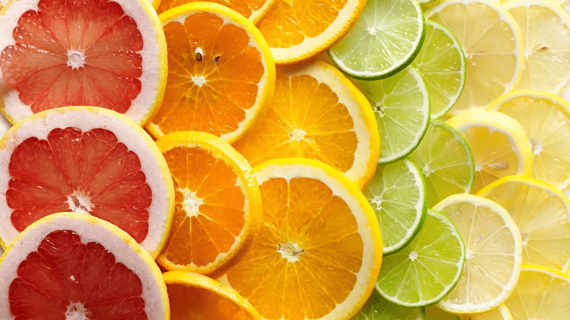 Vibrant overlaps of cut-up citrus fruits, starting with grapefruit rounds, then oranges, limes, and lemons.