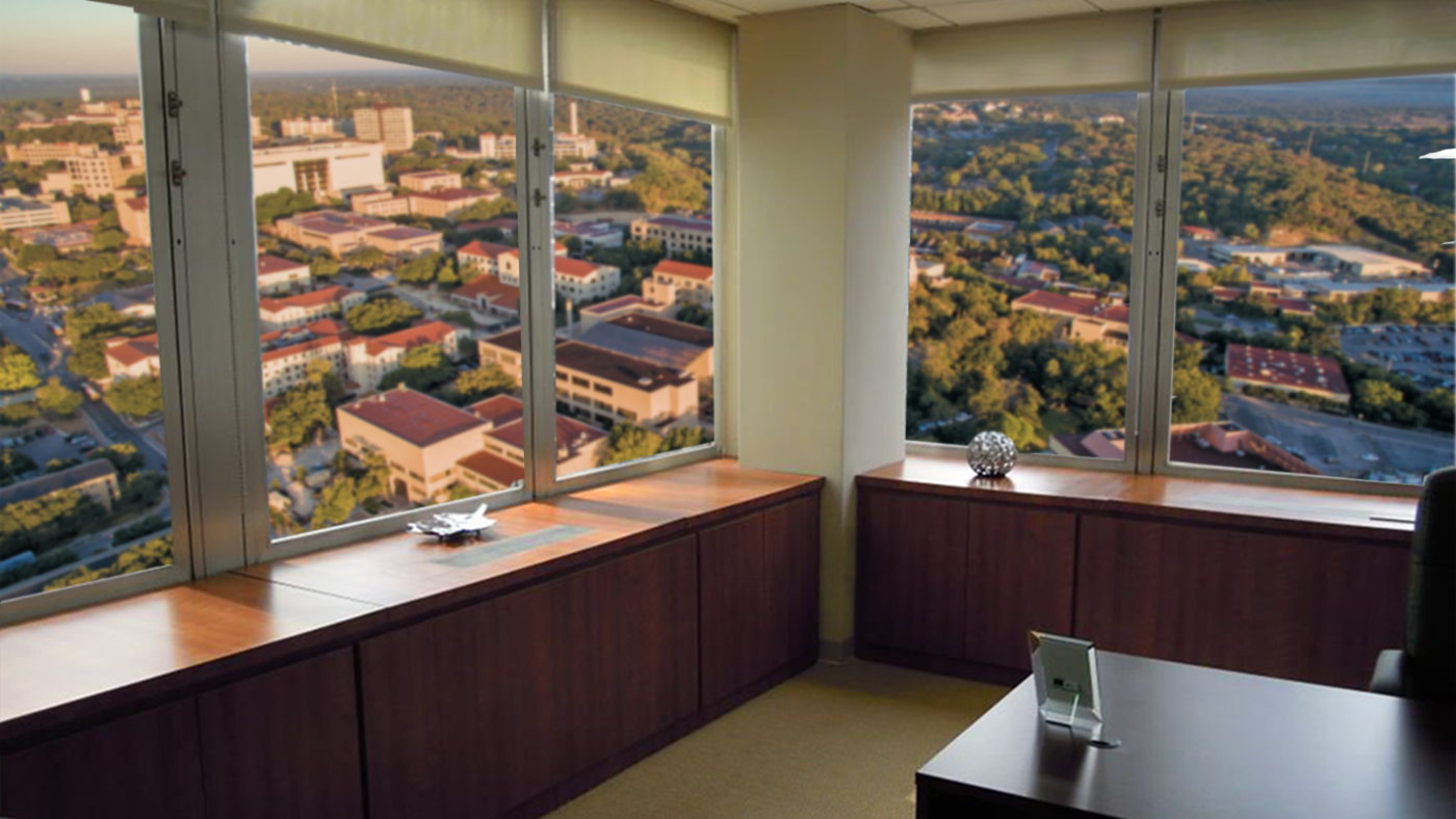 Top floor corner office at Texas State University with large windows and a view of the campus.
