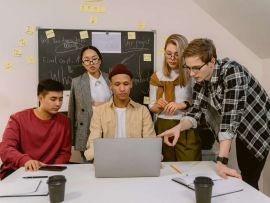 A group of people gathered around a laptop while working on a project.