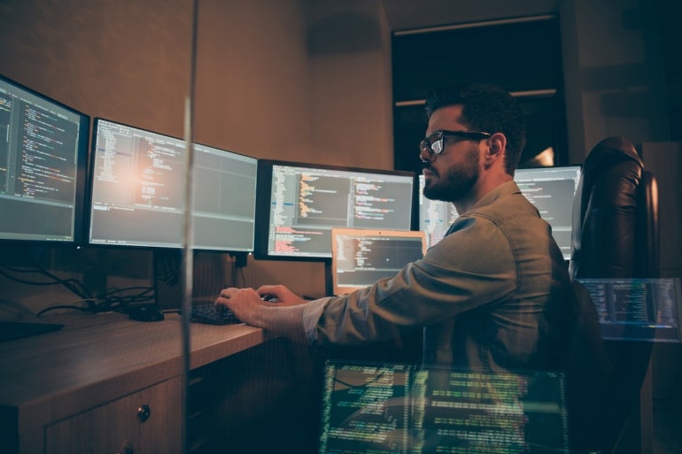 Photo of programmer serious writing code to software which will be involved into large projects connected with artificial intelligence analyzing time when the work may be finished