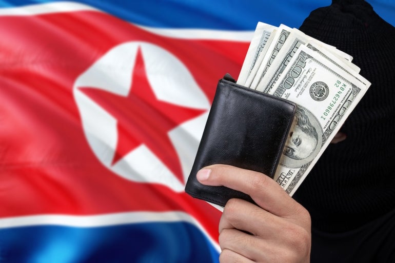 North Korea security and crime concept. Black criminals wear a head yarn, hold a dollar banknotes on national background.