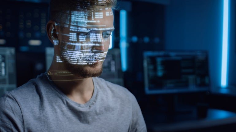 Handsome Young Software Developer Working on Personal Computer in Digital Identity Cyber Security Data Center, Program Coding Language Reflects on His Face. Futuristic Hacking and Programming Concept