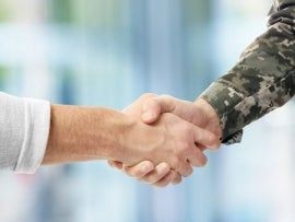 Soldier and civilian shaking hands on white background, closeup