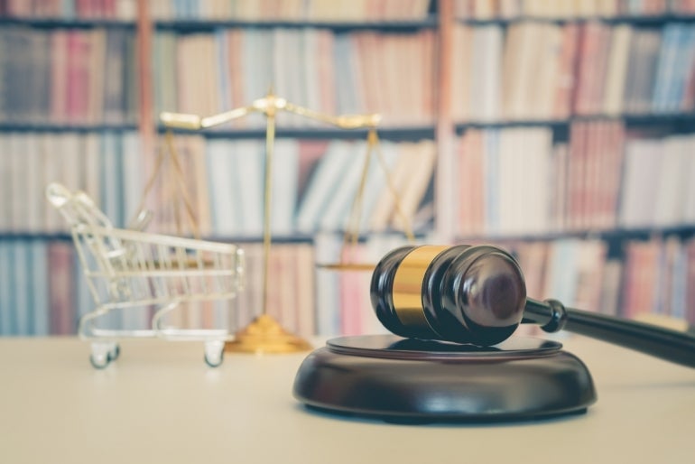 gavel next to a scale that has a mini shopping cart