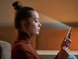 Female scans face using facial recognition system on smartphone for biometric identification. Future digital high tech technology and face id