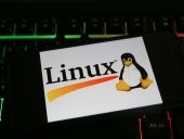 Closeup of mobile phone screen with logo lettering of linux on computer keyboard.