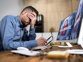 Ransomware on a screen and a person with his head in his hands.