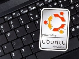 Powered by Ubuntu GNU Linux operating system sticker, logo symbol label closeup, laptop keyboard. Debian open source software technology concept, top view
