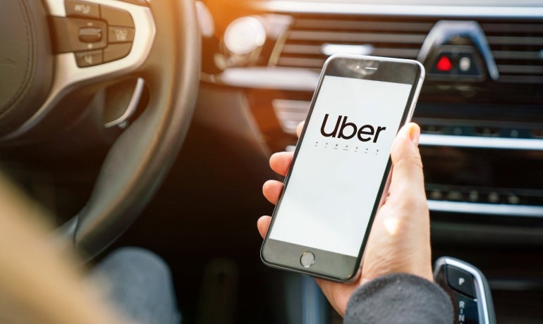 Uber driver holding his smartphone in car. 