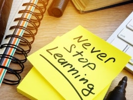 Never stop learning written on a memo stick. Lifelong learning concept.