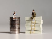 gender pay gap illustrated with two miniature people on a pile of bills and coins