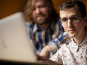 Two IT worker securing and optimizing an Apple computer.