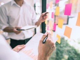 A group of employees planning on a window with sticky notes.