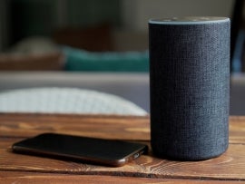 Dark grey Black Amazon Alexa Echo and smart phone on the wooden table in a living room.