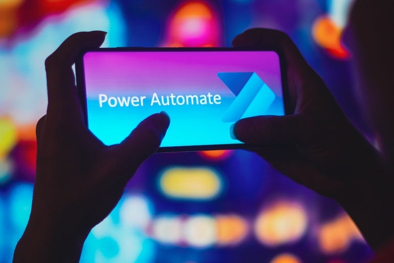 July 6, 2022, Brazil. In this photo illustration, a silhouetted woman holds a smartphone with the Microsoft Power Automate logo displayed on the screen.