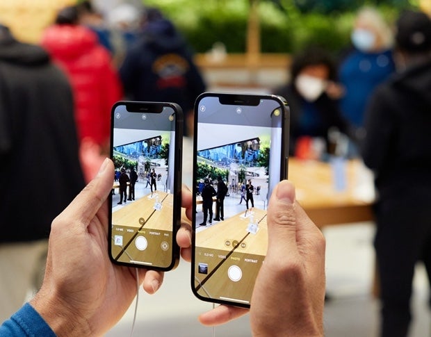 A man holding two iPhones running iOS16.