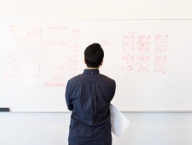 A man looking at project management planning on a whiteboard.