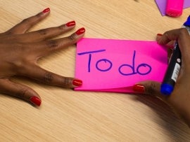 Hands holding a sticky note that reads To do.