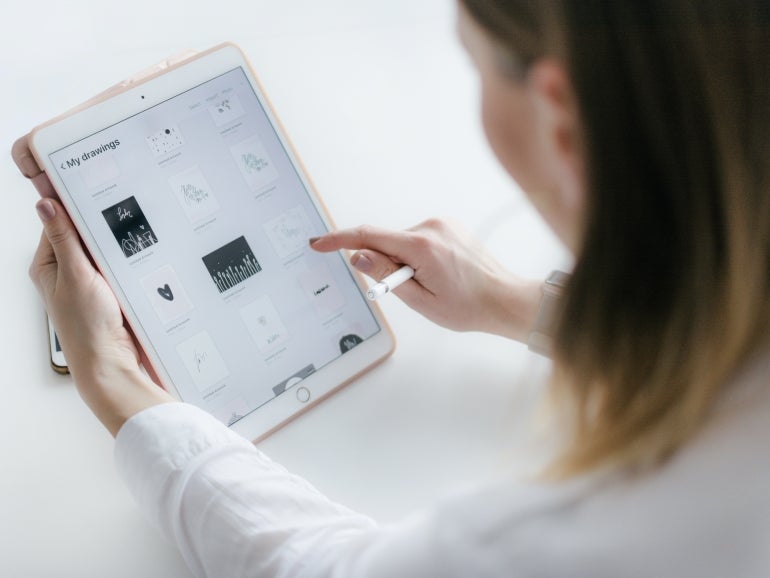 Woman using an iPad on her desk.