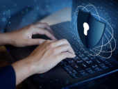 Hands typing on a computer with a security symbol.