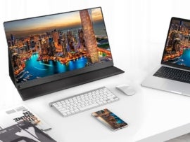 UPERFECT 15.6" Portable Monitor surrounded by a keyboard, laptop, phone, and magazinse