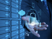 A hand holding a lock representing digital security in front of servers.