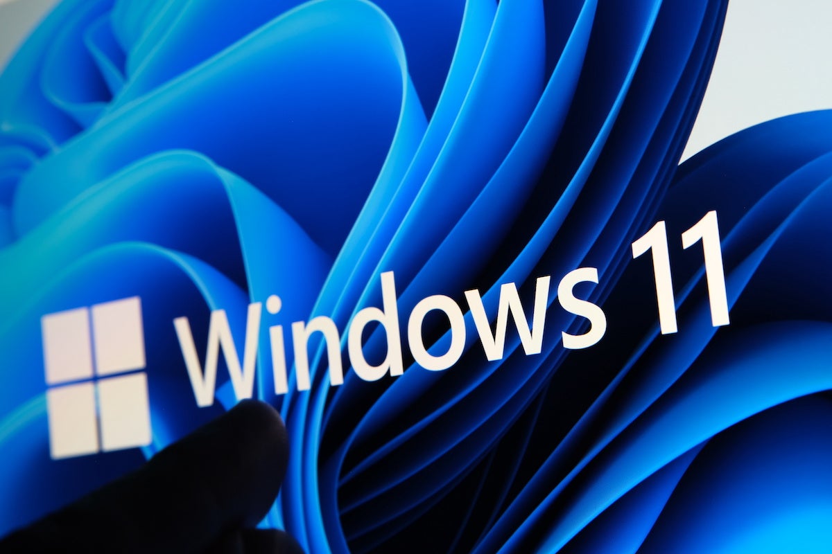 Windows 11 logo seen on the screen of tablet and user pointing at it with finger. Stafford, United Kingdom, July 1, 2021