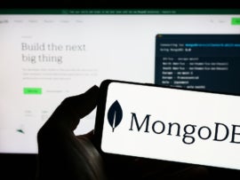 The MongoDB logo on a phone in front of the website.