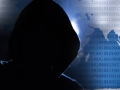 A hacker with their hood up in front of a world map covered in binary code.