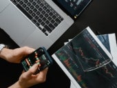 Man holding a phone with a stock trading app open on it