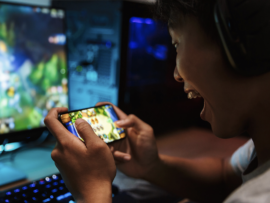 A gamer playing on mobile and desktop.