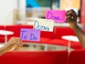 Two hands holding kanban sticky notes that say, "to do, doing, done."