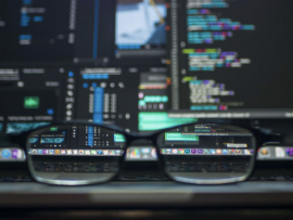 Glasses in front of a screen of code.