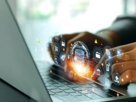 Person working on a laptop with data management related icons floating above the keyboard in white