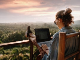Young business woman working on a laptop overlooking a scenic view.