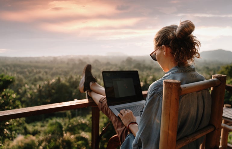 Young business woman working on a laptop overlooking a scenic view.