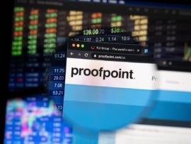 Proofpoint website on laptop with blurry stock market development in the background.