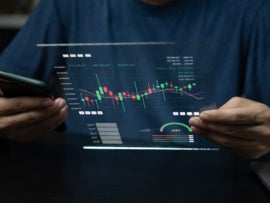 Man using a smartphone and a virtual screen showing charts and graphs.