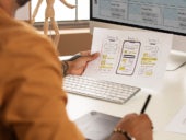 Man working on a design on his computer from a mock up.