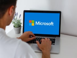 Man using a laptop with the Microsoft logo on display.