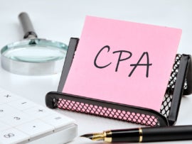 CPA, Certified Public Accountant word on the sticker on the stand on a white background next to a fountain pen, calculator and magnifying glass on a white background.