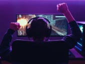 Back view of pro gamer wearing headset celebrating victory in online internet esport tournament, makes yes hands gesture, looking at monitor.