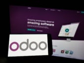 Person holding cellphone with logo of French software company Odoo on screen in front of business webpage.