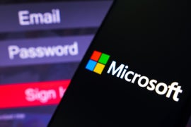 Microsoft Corporation logo is displayed on a smartphone screen, next to a login screen, with email, password and sign in.