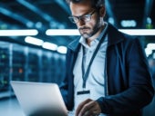 IT professional working on a laptop in data center.