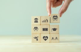 Hand stacking wooden cubes with inscripted employee benefit icons.