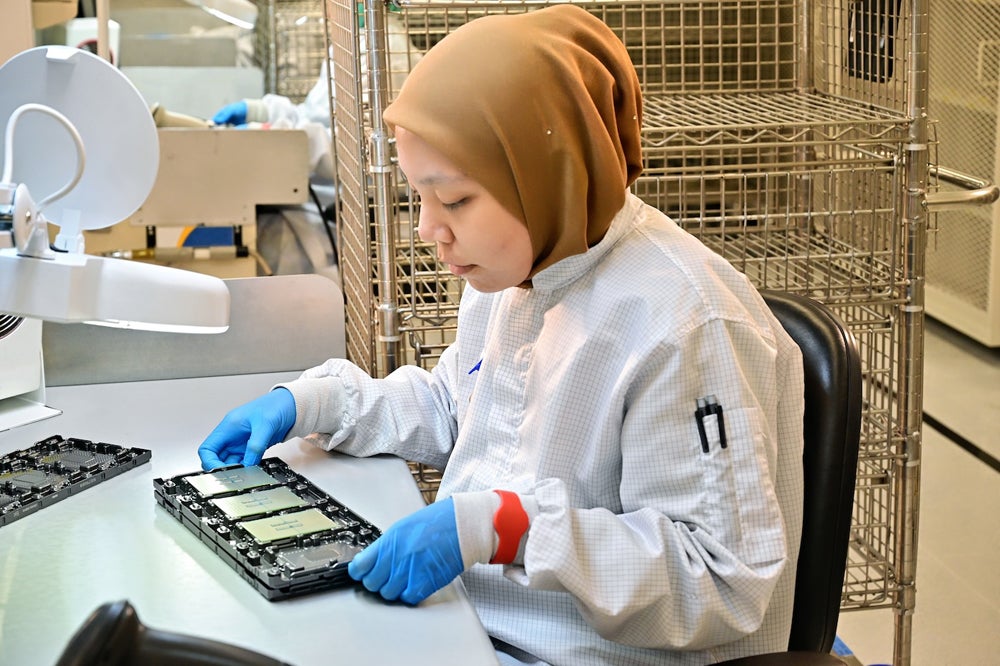 A worker at the Intel Kulim Test Assembly Test facility in Malaysia examines Intel Xeon 6 processors with E-cores.